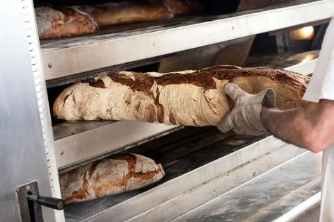 Baker taking large loaf of bread out Stock Photos