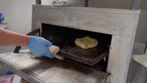 Baker taking out freshly baked adjarian khachapuri from oven Stock Footage 286309914