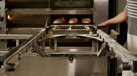 Baker taking out hot fresh white bread from the oven Stock Footage 64471074