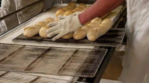 Baker taking out hot fresh baguettes to the tray Stock Footage 64471103