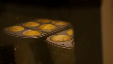 Baker taking out metal cupcake tray from oven baking rack A Stock Footage 111677108