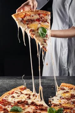 Baker taking off a slice of pizza with minced beef Stock Photos