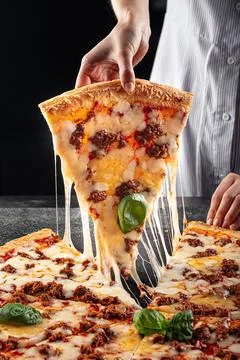 Baker taking off a slice of pizza with minced beef Stock Photos