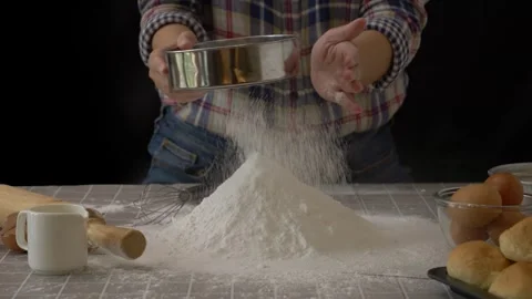 Baker use colander to sift flour into pile of flour for bread dough preparation Stock Footage 244986473