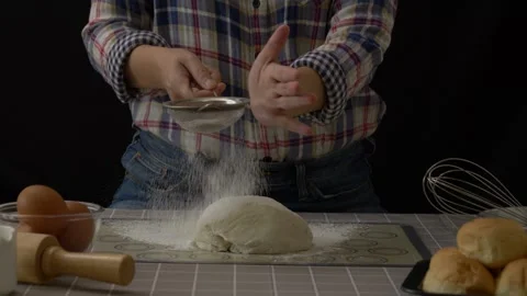 Baker use a sieve to sift flour into dough bread Stock Footage 244986393