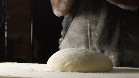 Baker wearing apron standing behind dough on counter Stock Footage 274688975