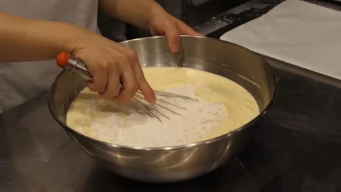 Baker Whisking Flour into Liquid Batter in Metal Bowl, Close-Up Video stock 345291447