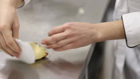 A baker in white uniform collects bread dough with his hands with a scraper Stock Footage 121036410
