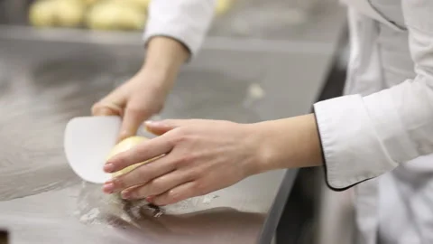 A baker in white uniform collects bread dough with his hands with a scraper Video stock 121036416
