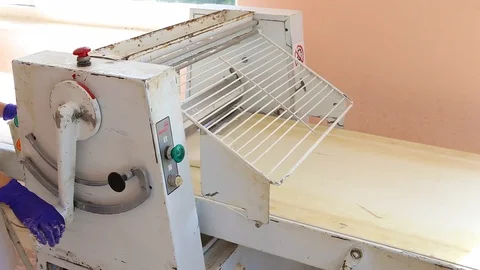Baker who uses a dough-making machine to make dough on a bakery for bread, bague Stock Footage 129305895