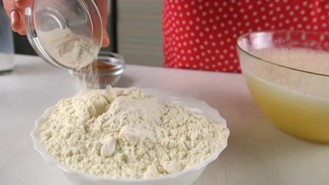 Baker woman adding baking powder to flour in white bowl cooking on kitchen. 스톡 동영상 311528025
