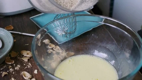 Baker woman's hands pouring ground up almonds into a bowl Stock Footage 75759547