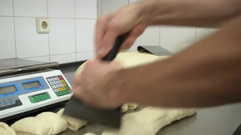 Baker working fast cutting raw bread rolls from a kneaded dough 스톡 동영상 251370636