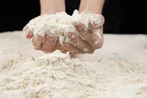 Baker working with white wheat flour, hands close-up. Stock Photos
