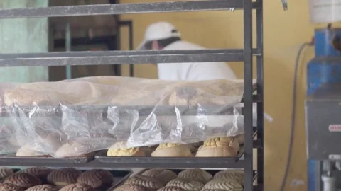 Bakers are hard at work in a bakery with freshly baked bread cooling on Stockbeeldmateriaal 285159904
