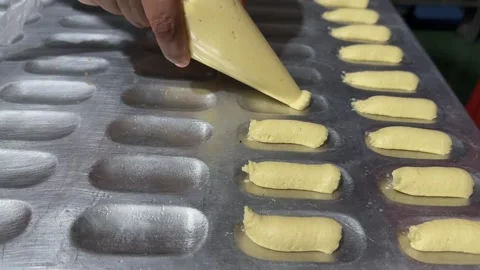 Baker's Hand Piping Batter into Metal Baking Mold, Close-Up Shot Video stock 325304053