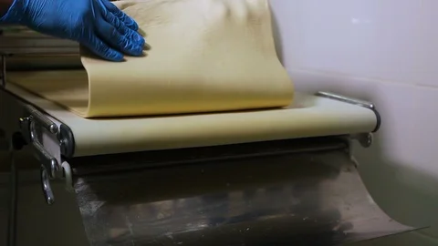 Baker's hands fold a long flat piece of dough Stock-Footage 106463609