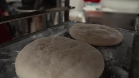 Baker's hands place two dough rounds on a metal tray, showcasing the preparation Vídeo Stock 331755455