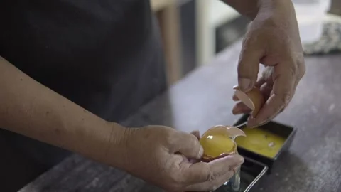 Baker's hands separating the yolks and whites of an egg Stock Footage 272498947