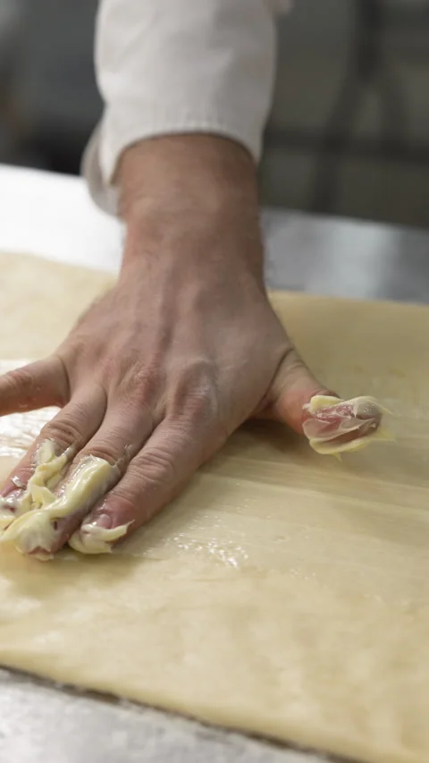 Bakers hands spreading butter over rolled dough preparing croissant or cinnabon Stock Footage 319040802