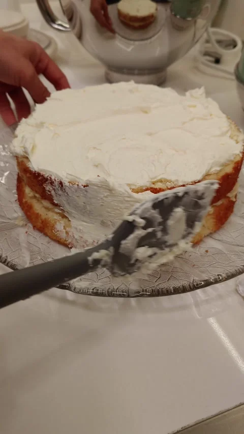 Baker's hands spreading delicious white cream frosting on a cake. Stock Footage 313299748