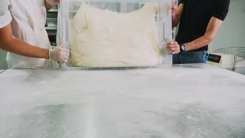 Bakers put large dough onto table in bakery slow motion Stock Footage 124583330