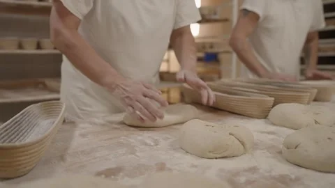 Bakers shaping bread dough on floured table in bakery, traditional bread making Видео 333349004