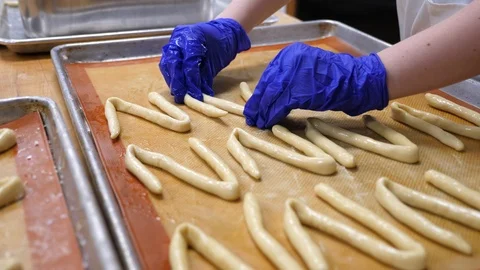 Bakery attendant makes bread pretzels and shapes them on tray at zermatt reso Stock Footage 89358879