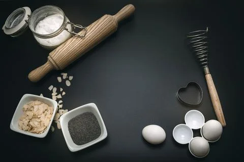 Bakery background. Baking ingredients and kitchen utensils on the black bac.. Stock Photos