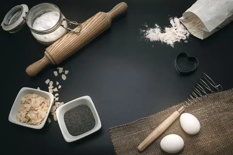 Bakery background. Baking ingredients and kitchen utensils on the black bac.. Stock Photos