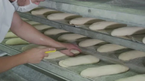 Bakery baking bakery. The worker makes patterns on the buns with a baking knife. Stock Footage 132784353