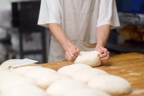 The bakery chef prepares the dough for baking bread. The baker kneads the d.. Stock-Fotos
