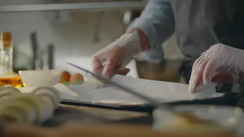 Bakery. A creative chef dressed in comfortable work clothes places parchment Stock Footage 276104703