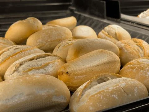 A bakery display features numerous fresh, golden-brown bread rolls with rus.. Stock Photos