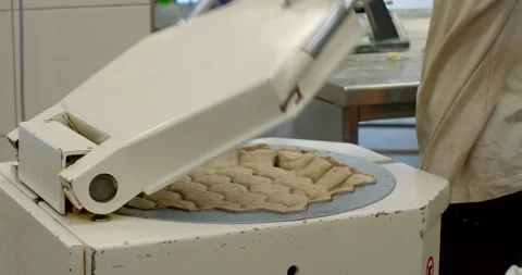 Bakery dough press in commercial kitchen with operator handling molded, with Stock Footage 344596104