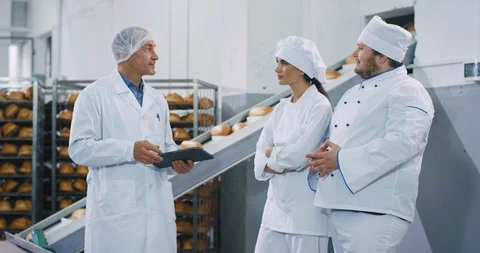 Bakery industry automated conveyor engineer explaining something to the bakers Stock Footage 112343570