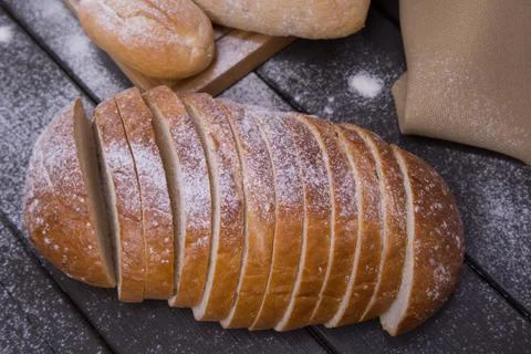 Bakery - sliced golden rustic crispy loaves of bread and buns on black chalkb Stock Photos