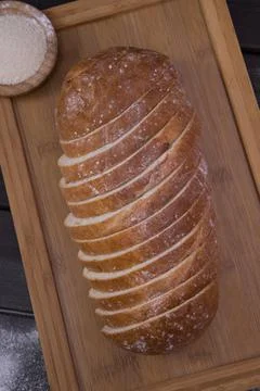 Bakery - sliced golden rustic crispy loaves of bread and buns on black chalkb Stock Photos