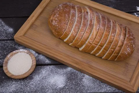 Bakery - sliced golden rustic crispy loaves of bread and buns on black chalkb Stock Photos