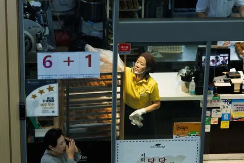 Bakery Worker Arranging Fresh Bread Inside Small Bakery in South Korea Stock Photos