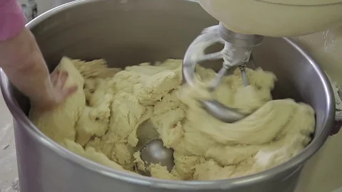 The bakery worker hands helps stir the dough in the kneader. Stock Footage 76476008