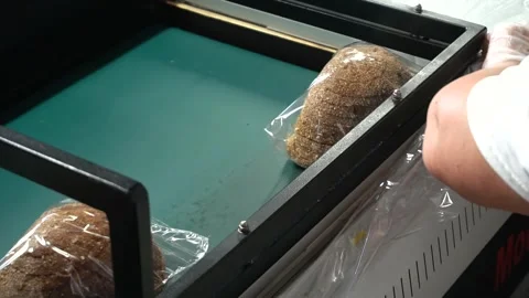 Bakery worker packs sliced ​​bread using a specialized packaging machine. Stock Footage 245385504