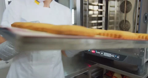 Bakery worker is taking out an oven sheet with gingerbread cookies, 4k Stock Footage 151820641