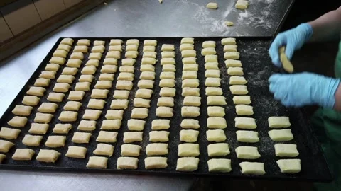 A bakery worker uses her hands to place pastries on a baking sheet Stock Footage 320307989