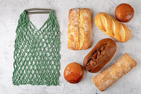 Baking background with eco string bag and whole fresh baked loaves of bread Stock Photos