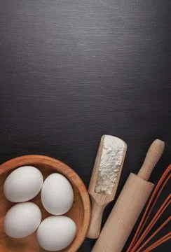 Baking background with flour, eggs, kitchen tools, utensils  on dark table... Stock Photos