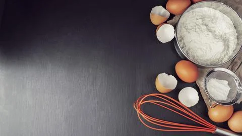 Baking background with flour, eggs, kitchen tools, utensils  on dark table... Stock Photos