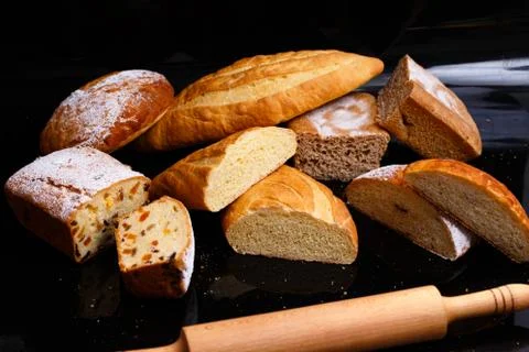 Baking on a black background with a rolling pin. Lots of pastries and bread. Stock Photos
