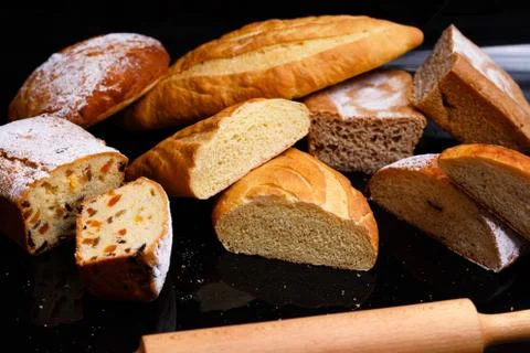 Baking on a black background with a rolling pin. Lots of pastries and bread. Stock Photos