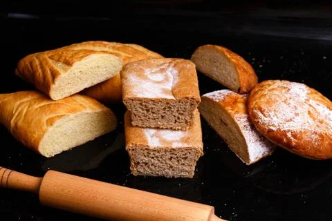 Baking on a black background with a rolling pin. Lots of pastries and bread. Stock Photos